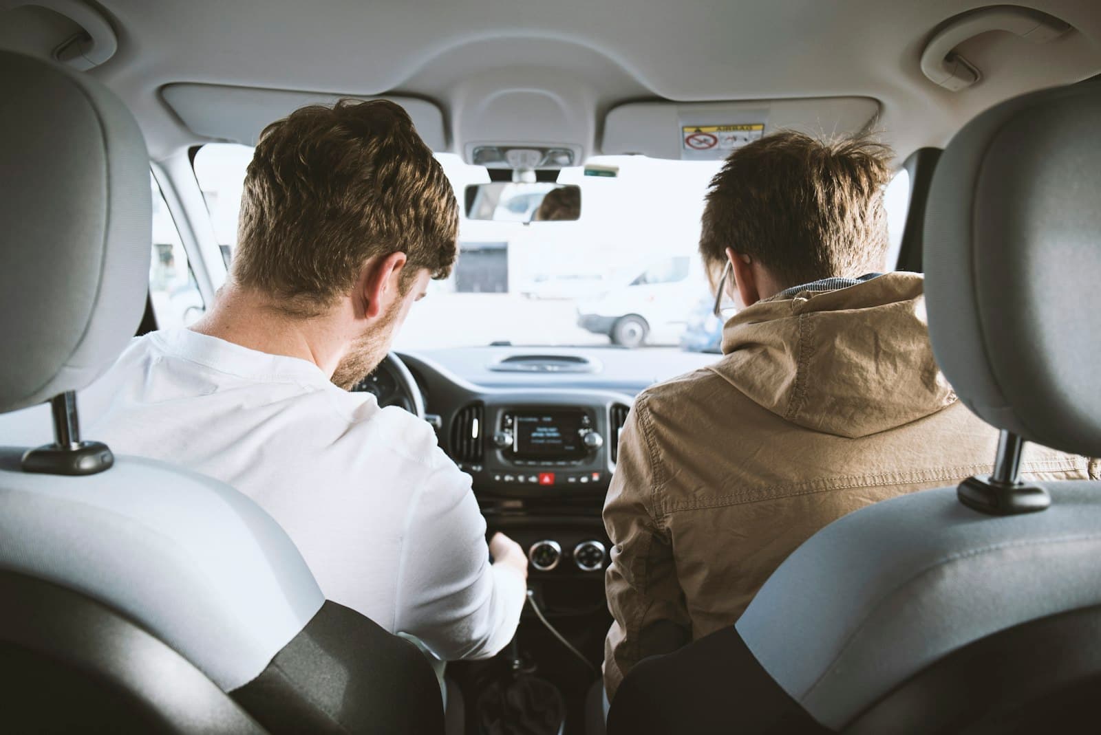 A passenger’s view of two people in the front of a car